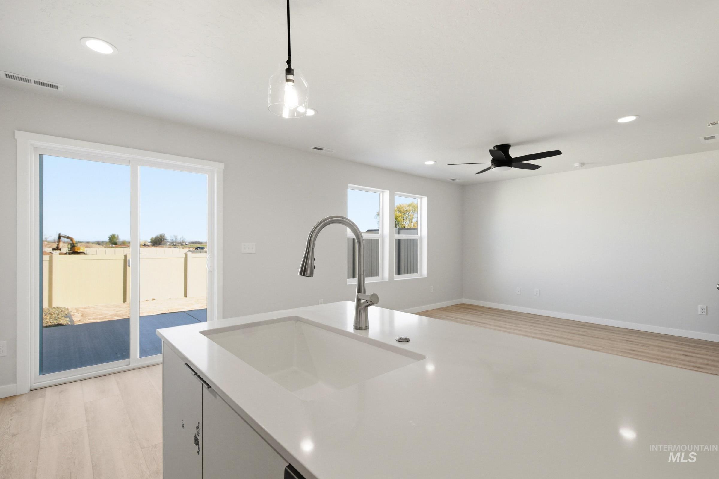 10806 Rutland Street Caldwell, ID 83605 - Photo 6 of 21 Kitchen island featuring an undermount sink with gooseneck faucet, light-toned countertop, and recessed lighting