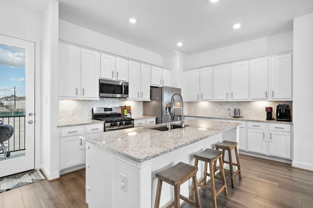 a kitchen with granite countertop white cabinets and stainless steel appliances