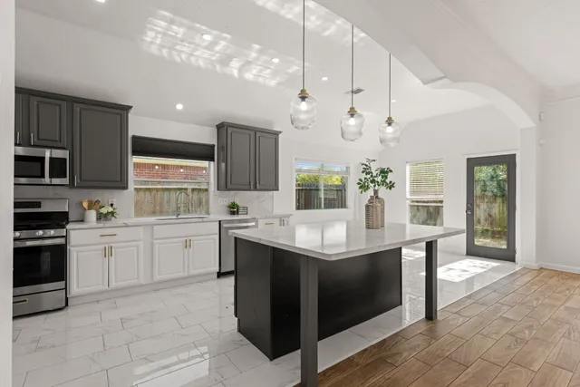 a kitchen with kitchen island stainless steel appliances a sink stove and cabinets