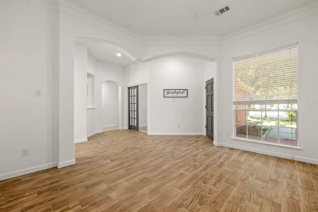 a view of an empty room with wooden floor and a window
