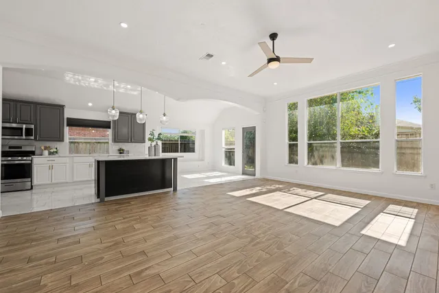 a large kitchen with kitchen island a large counter top a sink stainless steel appliances and cabinets