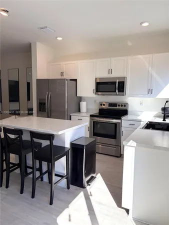 a kitchen with stainless steel appliances kitchen island granite countertop a table chairs sink and cabinets