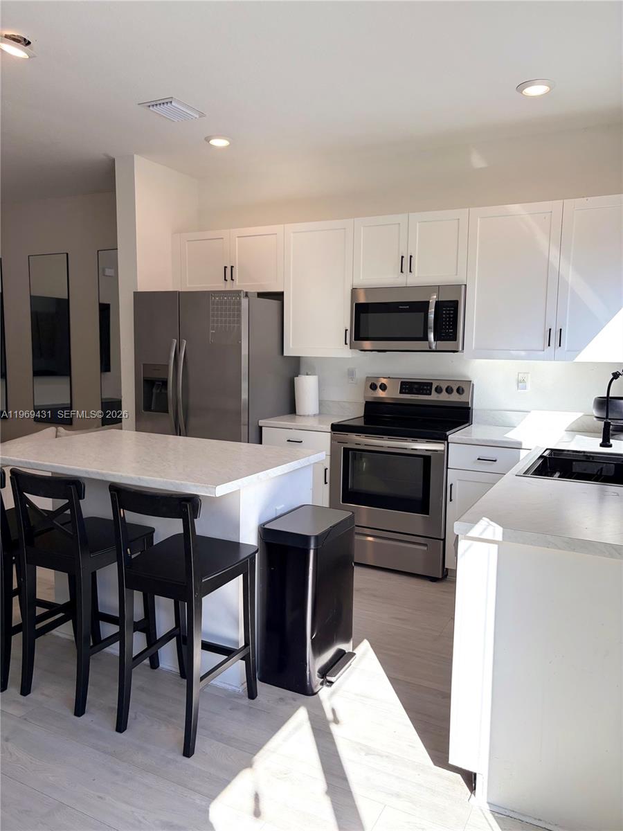 14724 Southwest 181st Terrace Miami, FL 33187 - Photo 18 of 36 a kitchen with stainless steel appliances kitchen island granite countertop a table chairs sink and cabinets