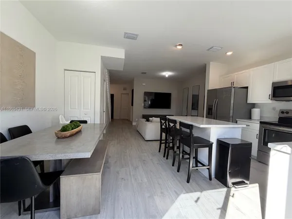 a kitchen with stainless steel appliances a dining table chairs stove top oven and sink