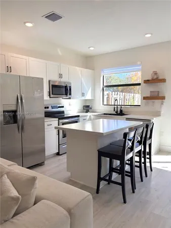 a kitchen with kitchen island a dining table chairs and a refrigerator