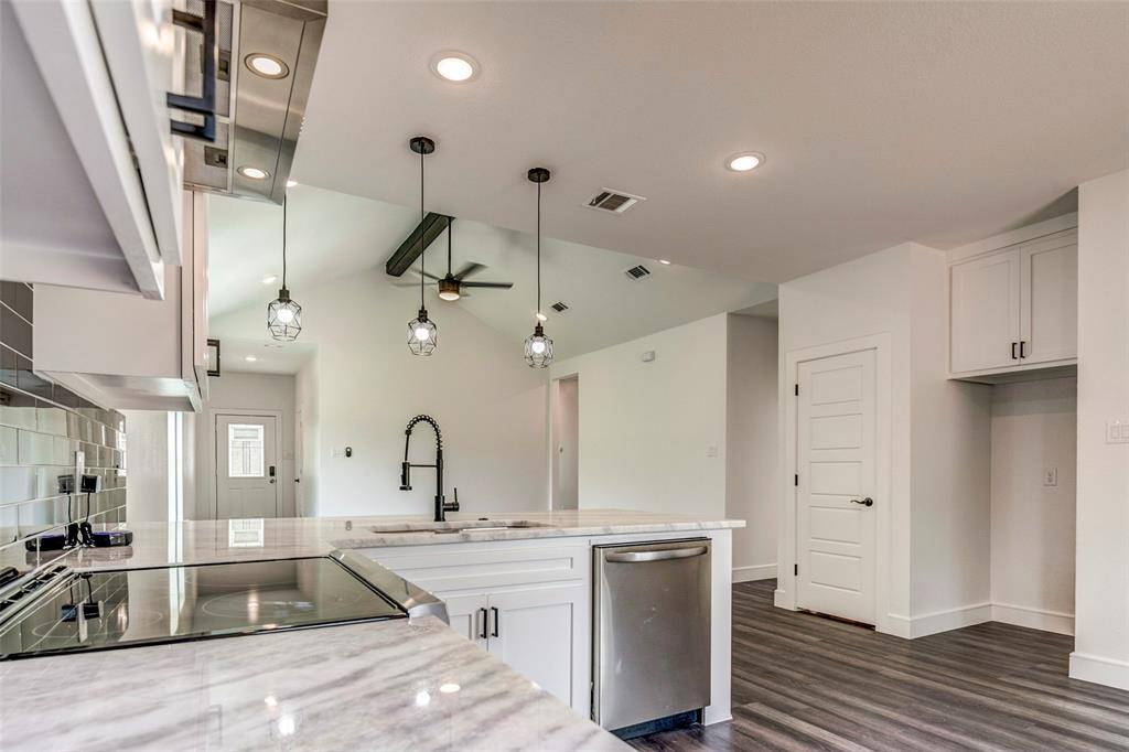 a large kitchen with stainless steel appliances kitchen island granite countertop a sink and a refrigerator