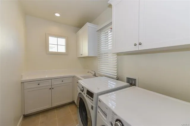 a utility room with a sink a cabinetry and a window