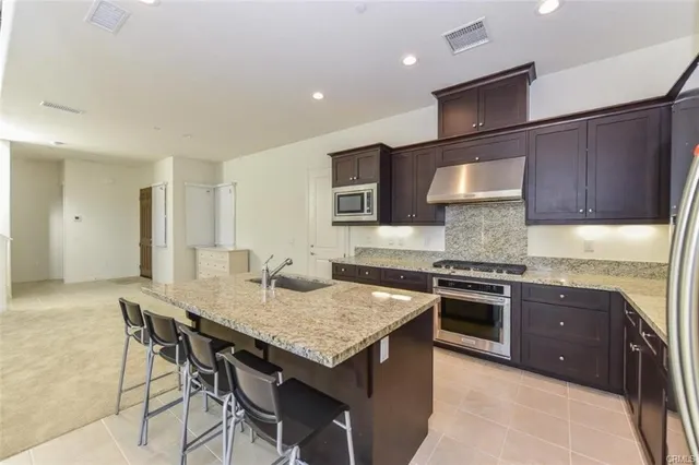 a kitchen with granite countertop a stove top oven a sink dishwasher and cabinets with wooden floor