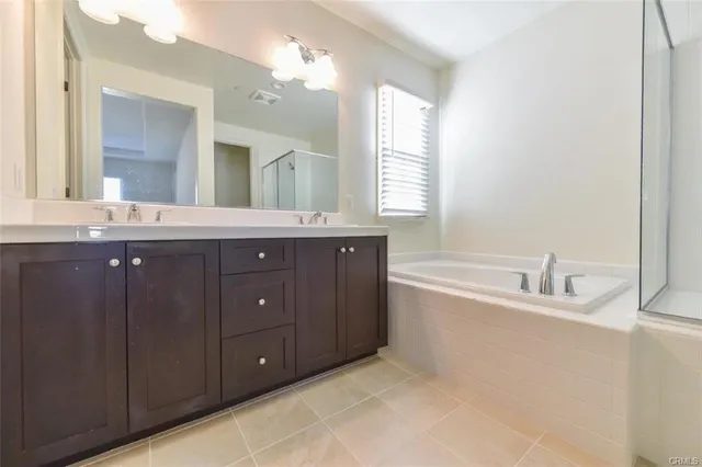 a spacious bathroom with double vanity sink a bathtub and a window