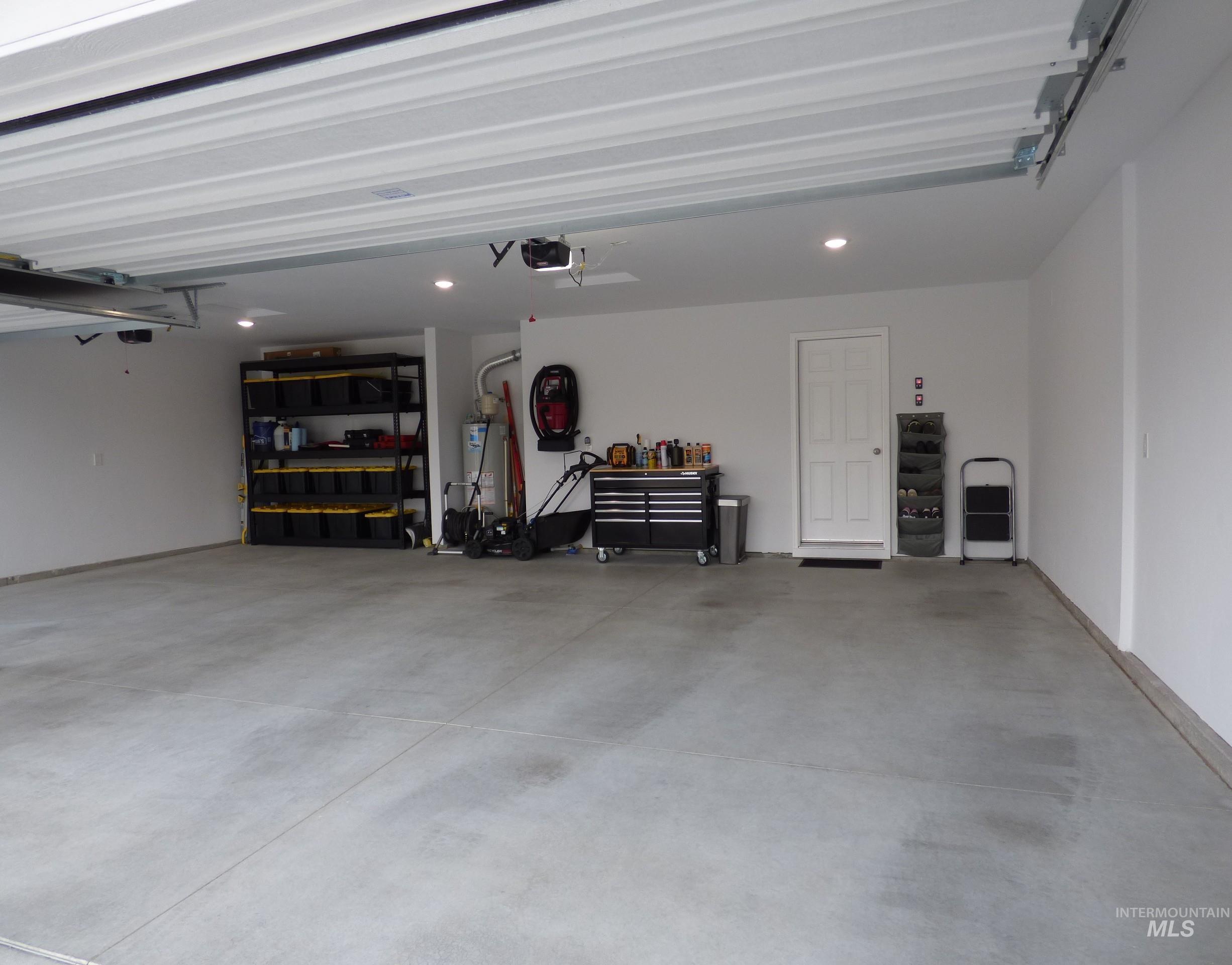 2708 East Buckaroo Drive Kuna, ID 83634 - Photo 34 of 48 Spacious garage featuring a concrete floor, bright white walls, recessed lighting, and an overhead garage door mechanism