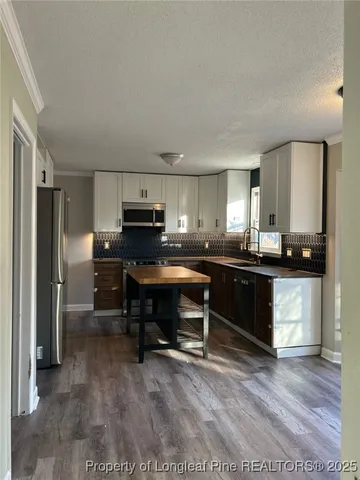 a kitchen with kitchen island a sink cabinets and stainless steel appliances