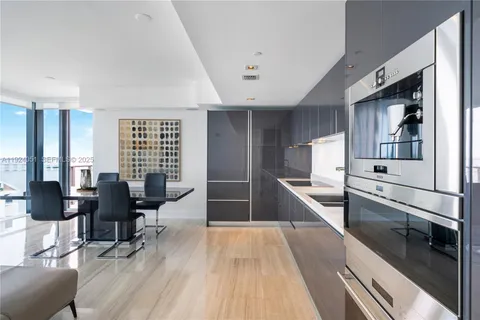 a large white kitchen with stainless steel appliances kitchen island granite countertop a large counter top furniture and a wooden floor