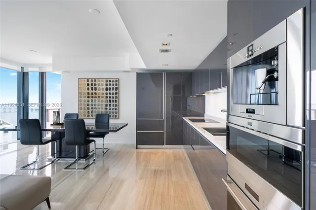 a large white kitchen with stainless steel appliances kitchen island granite countertop a large counter top furniture and a wooden floor