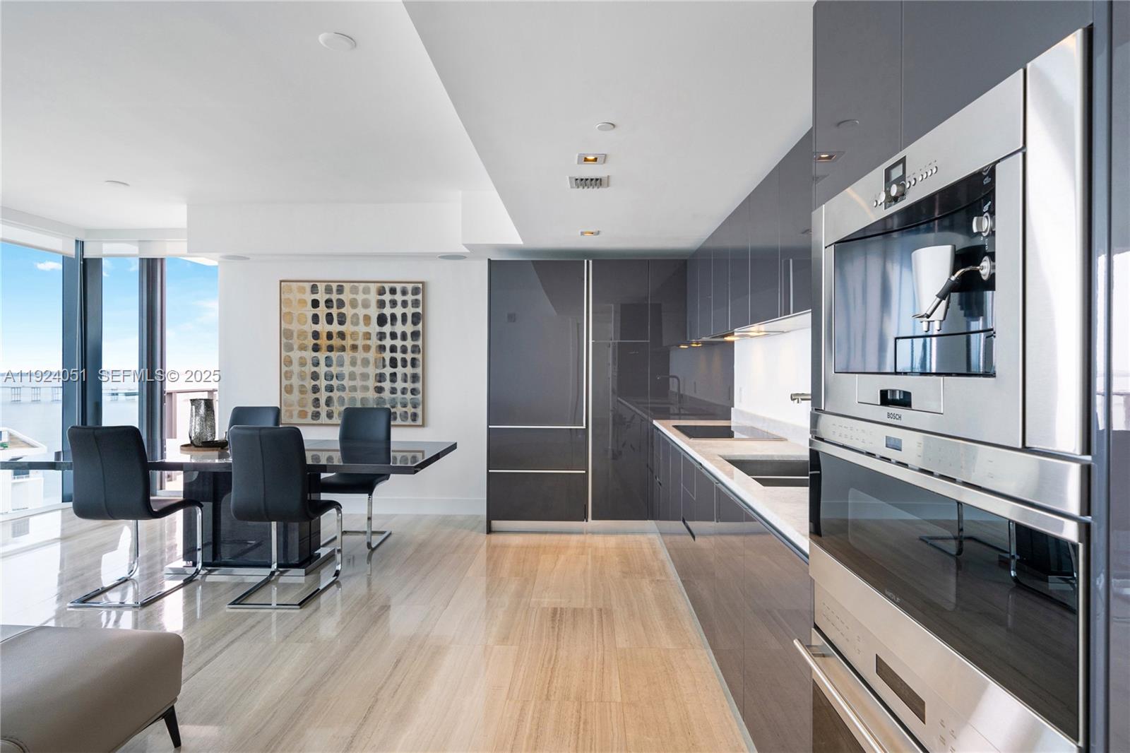 1451 Brickell Avenue, Unit 2003 Miami, FL 33131 - Photo 12 of 36 a large white kitchen with stainless steel appliances kitchen island granite countertop a large counter top furniture and a wooden floor