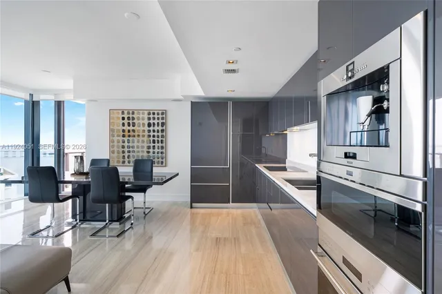 a large white kitchen with stainless steel appliances kitchen island granite countertop a large counter top furniture and a wooden floor