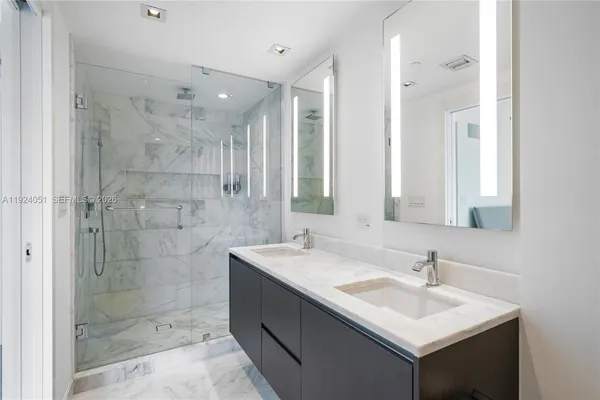 a bathroom with a sink shower and a mirror