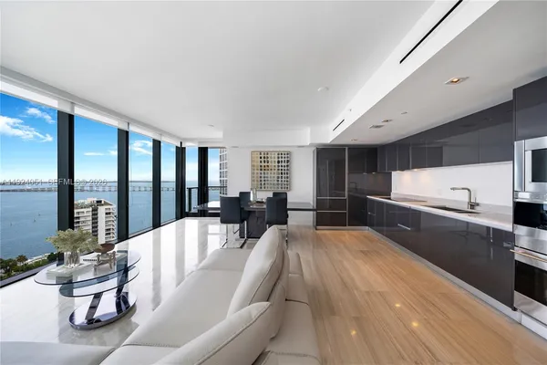 a large white kitchen with a large window and stainless steel appliances