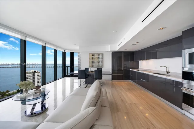 a large white kitchen with a large window and stainless steel appliances