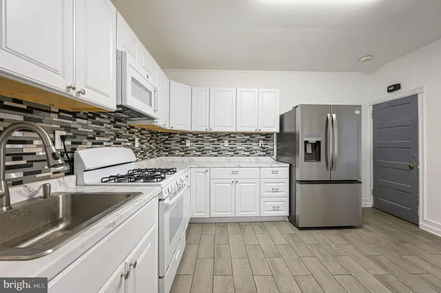 a kitchen with granite countertop a refrigerator sink stove and cabinets
