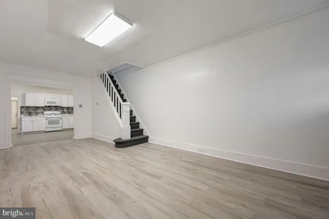 a view of an empty room with wooden floor and staircase