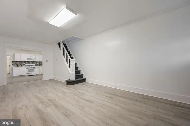 a view of an empty room with wooden floor and staircase
