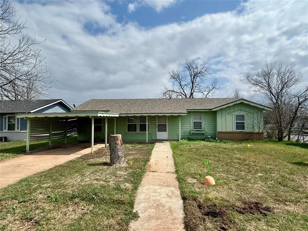 a front view of a house with a yard and trees