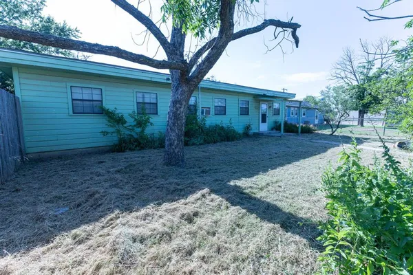 a view of a yard in front of a house with large trees