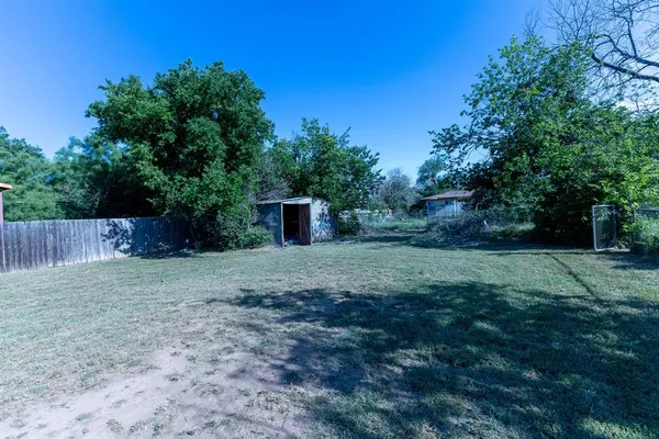 a view of a backyard with large trees and wooden fence