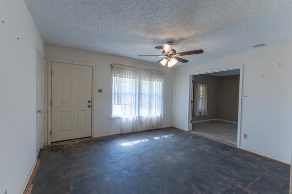 a view of an empty room with chandelier fan and window