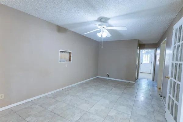 an empty room with chandelier fan and windows