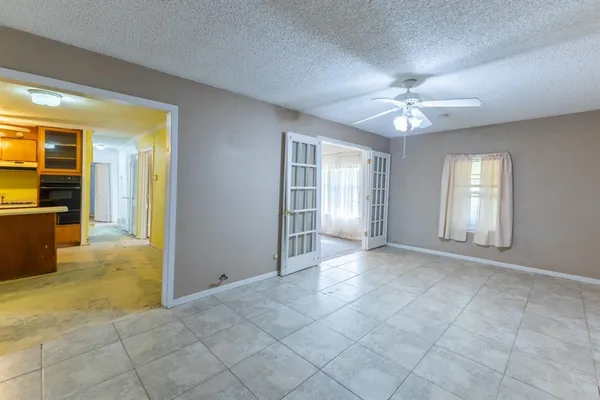 an empty room with chandelier fan and windows
