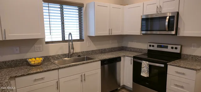 a kitchen with granite countertop a sink a stove and cabinets