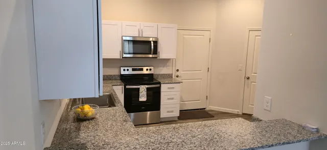 a kitchen with stainless steel appliances granite countertop a stove a microwave and a refrigerator