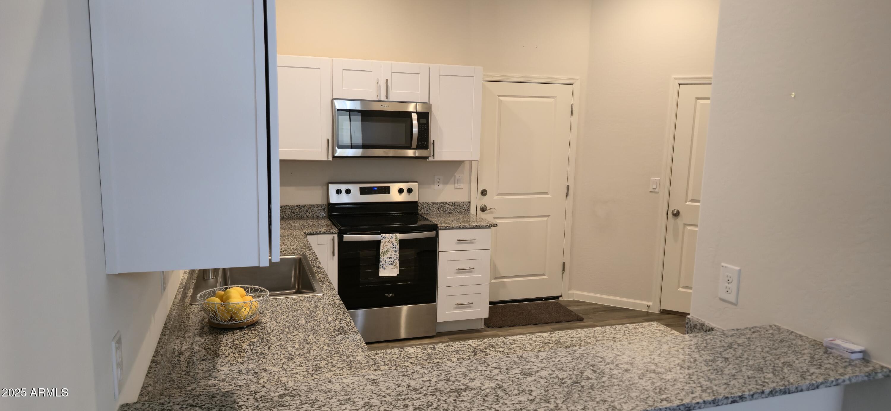 701 Dylan Court Wickenburg, AZ 85390 - Photo 5 of 29 a kitchen with stainless steel appliances granite countertop a stove a microwave and a refrigerator
