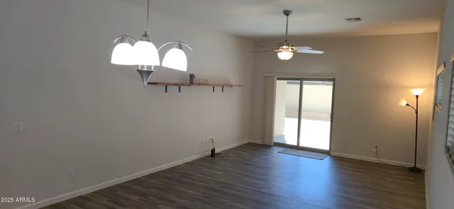 an empty room with wooden floor chandelier and window