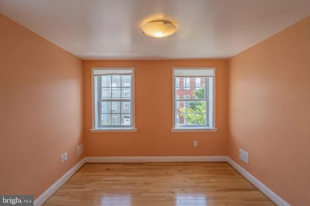 an empty room with wooden floor and windows