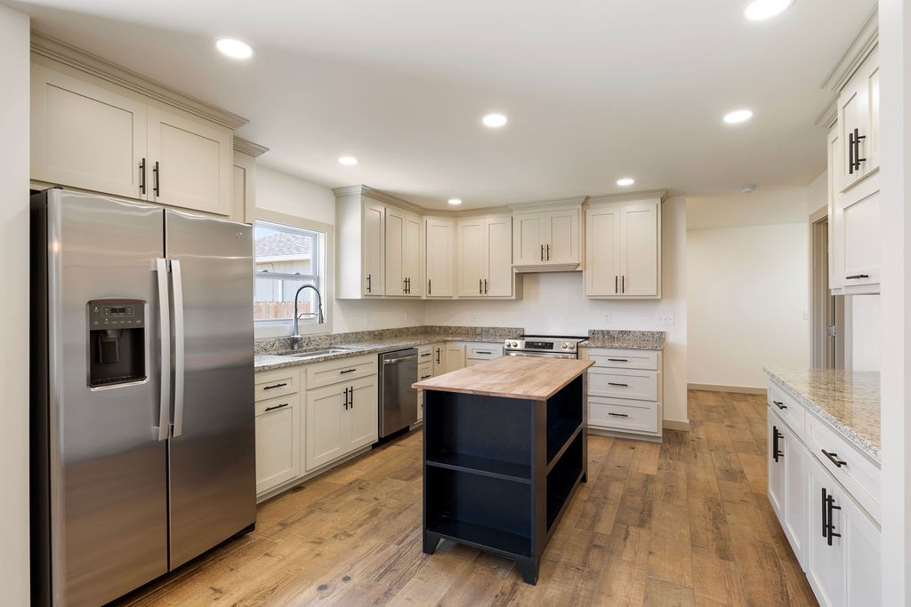 198 Beartown Road Loretto, TN 38469 - Photo 15 of 36 a kitchen with stainless steel appliances granite countertop a refrigerator a sink dishwasher a stove and white countertops with wooden floor