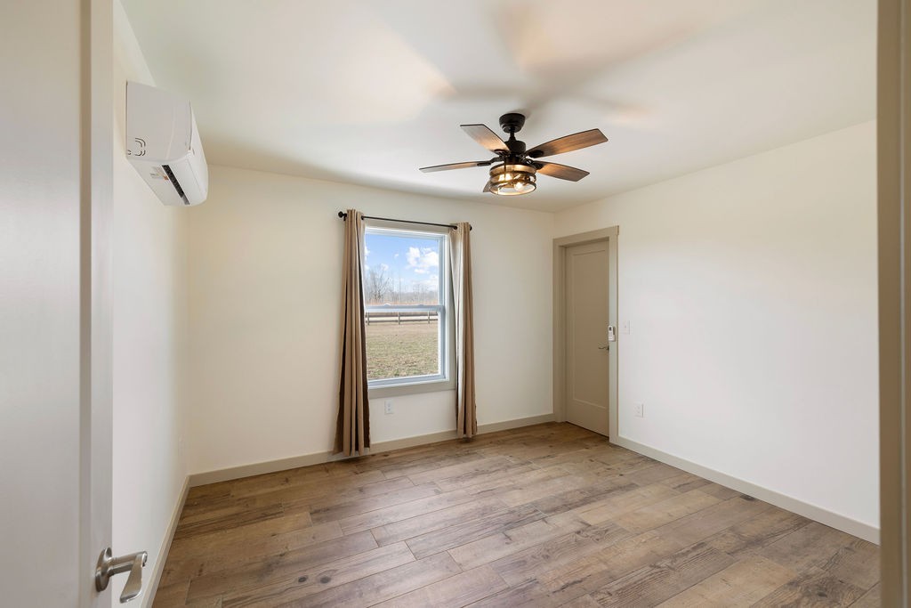 198 Beartown Road Loretto, TN 38469 - Photo 21 of 36 an empty room with wooden floor chandelier fan and windows