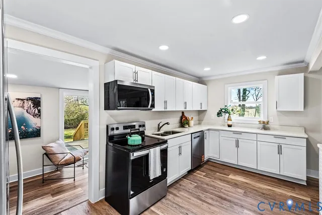 a kitchen with a sink a stove cabinets and wooden floor