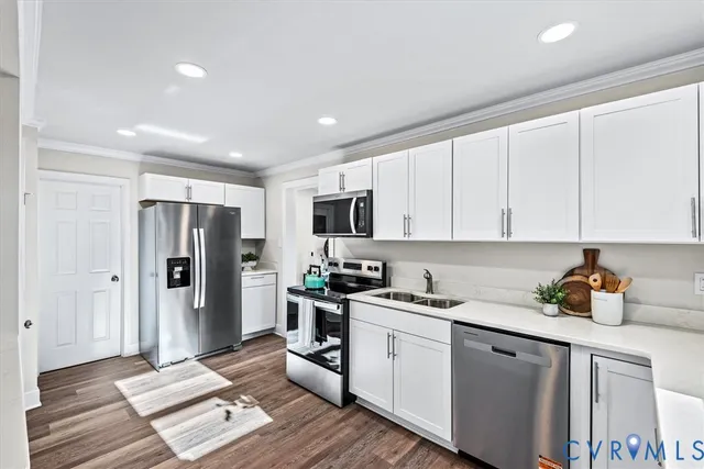 a kitchen with stainless steel appliances granite countertop a stove top oven a sink a refrigerator white cabinets and wooden floor