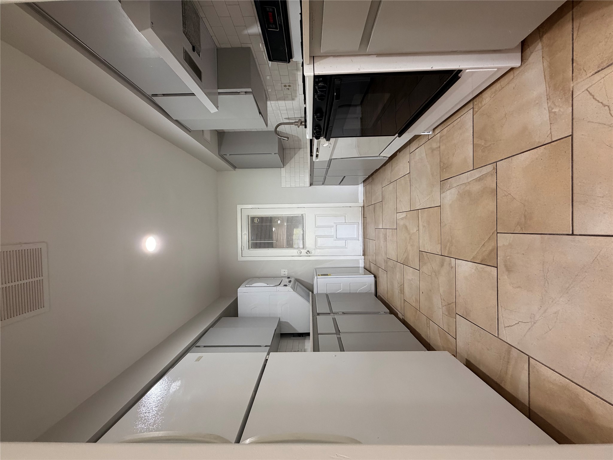 604 Gaylor Street, Unit A Austin, TX 78752 - Photo 3 of 5 A well-equipped galley kitchen boasts ample cabinetry and durable tile flooring, perfect for daily living.