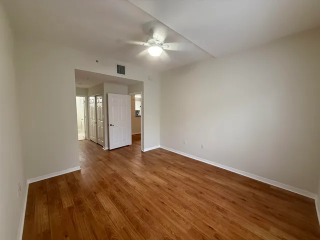 a view of an empty room with wooden floor and a mirror