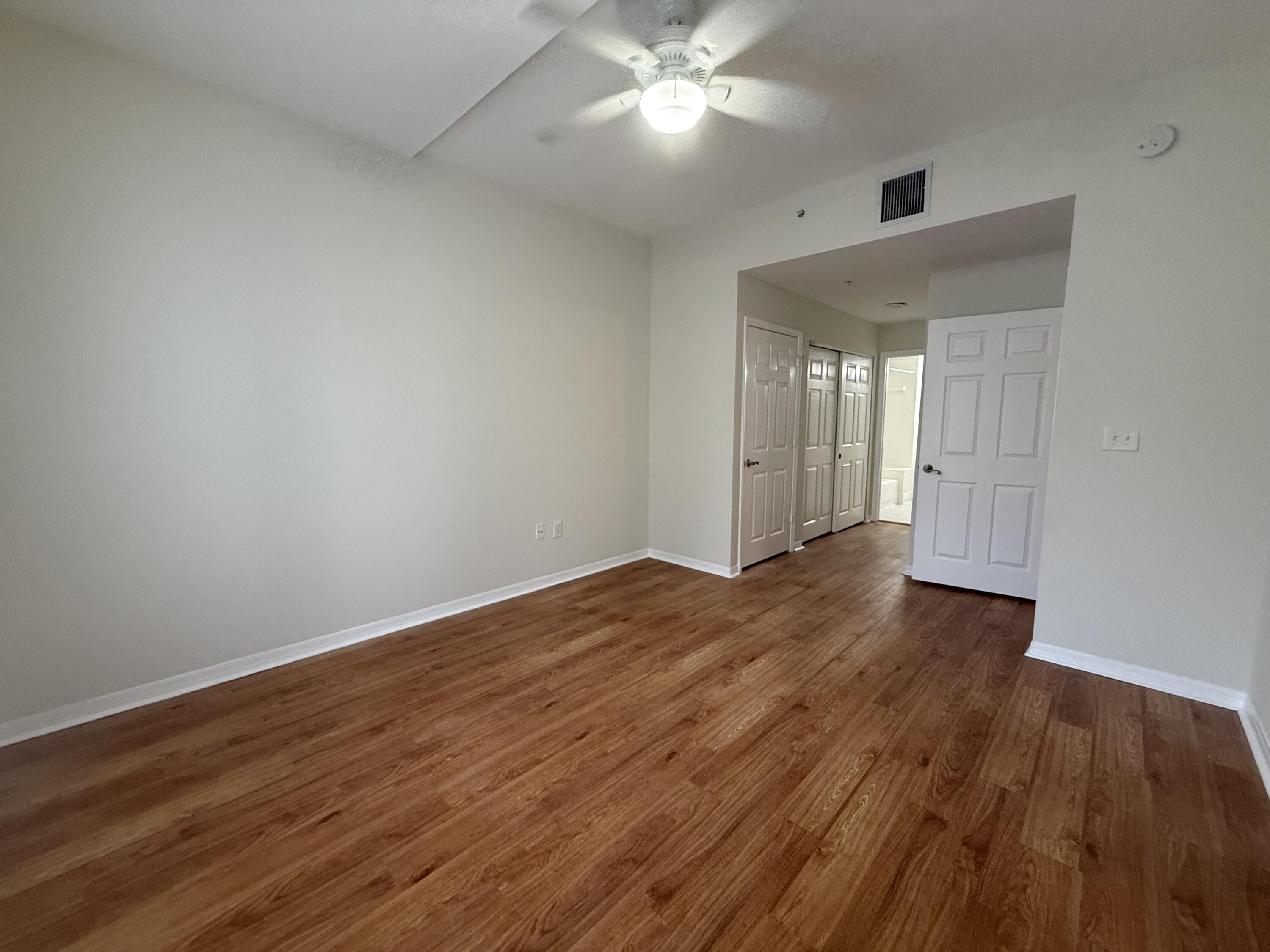 1200 Town Center Drive, Unit 206 Jupiter, FL 33458 - Photo 12 of 24 a view of an empty room with wooden floor and a ceiling fan