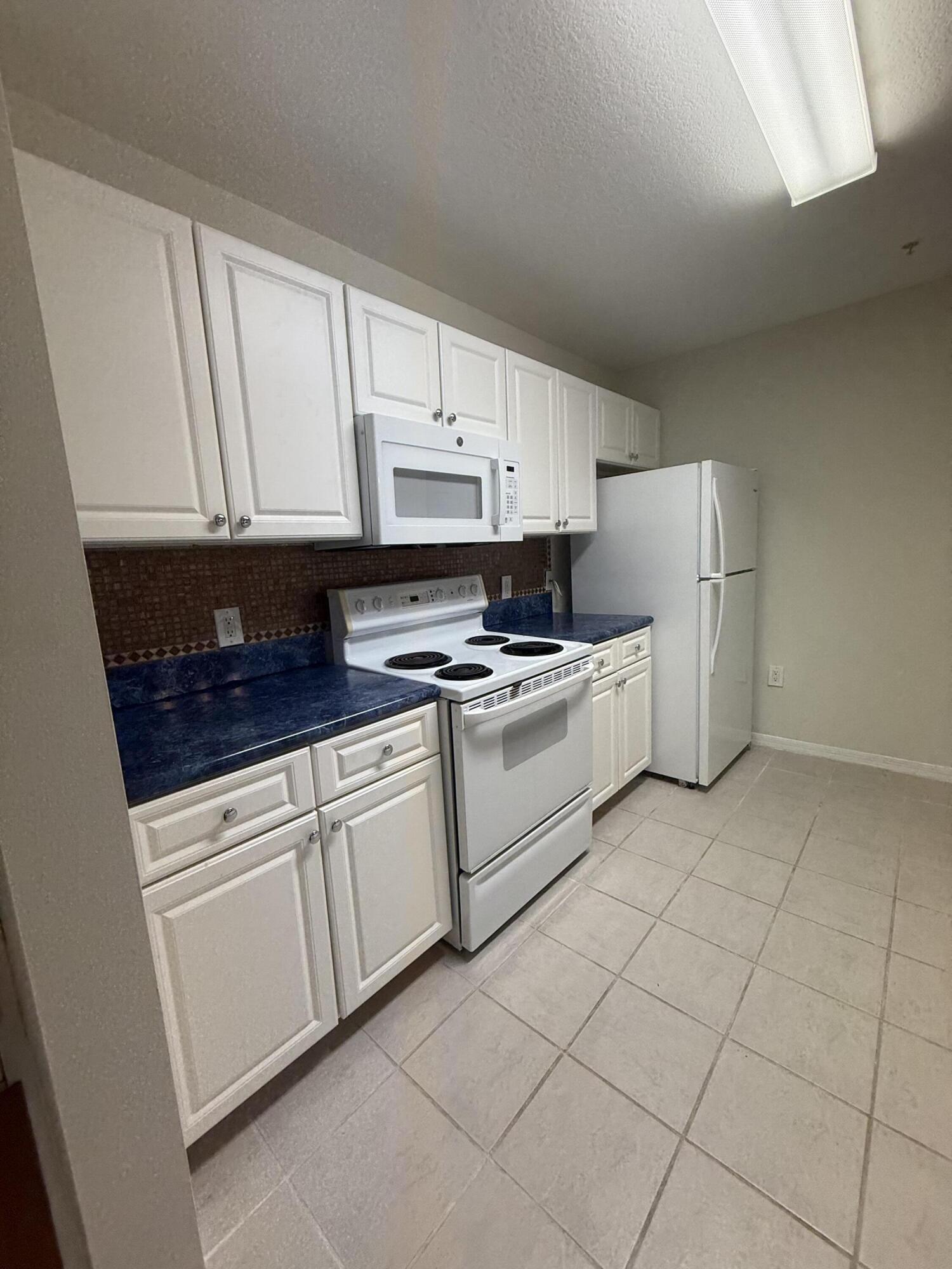 1200 Town Center Drive, Unit 206 Jupiter, FL 33458 - Photo 18 of 24 a kitchen with cabinets and white appliances
