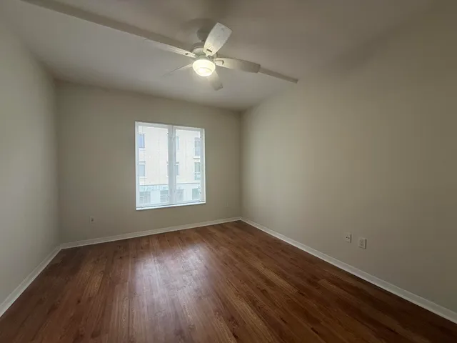 a view of an empty room with wooden floor and a window