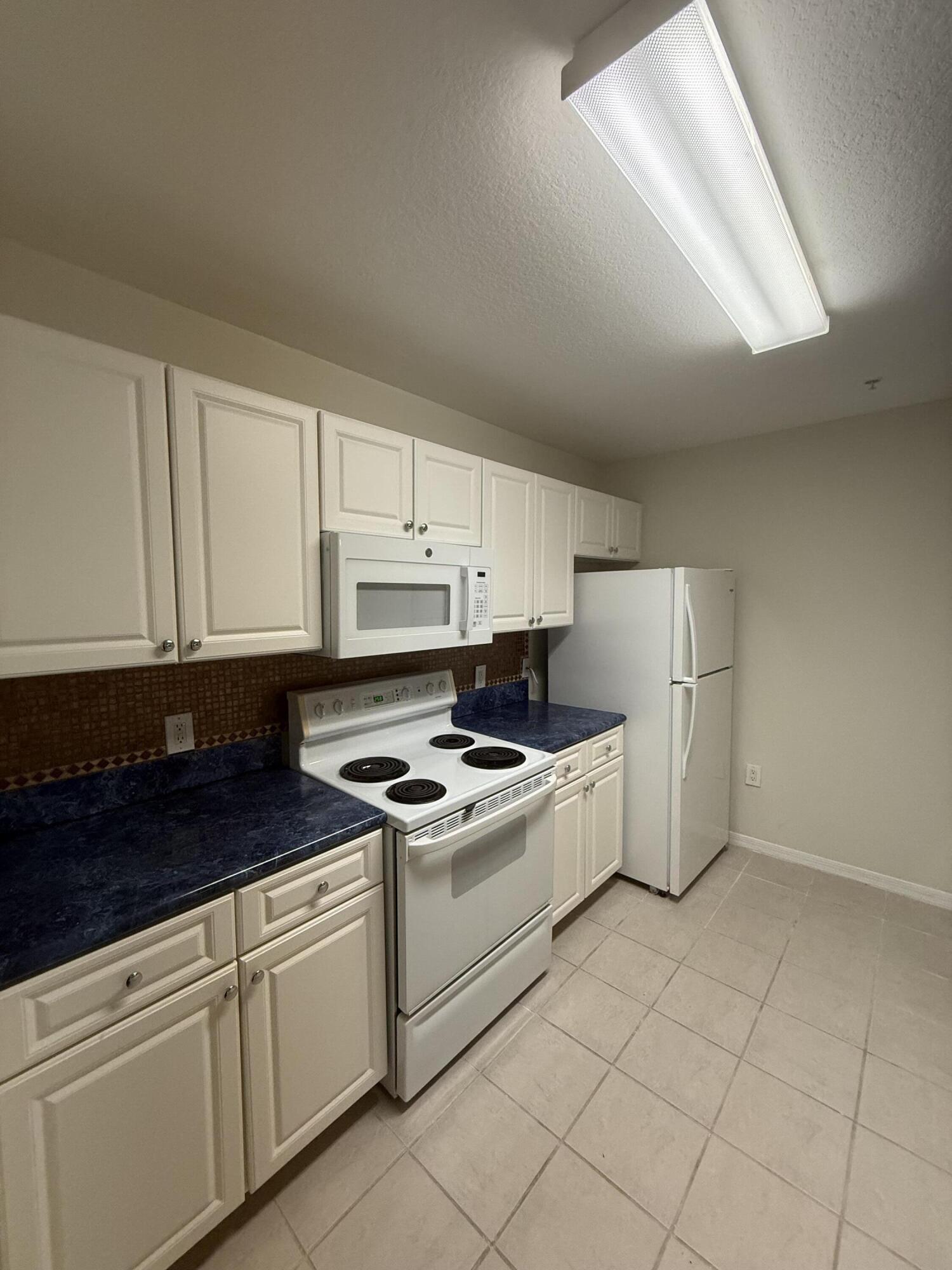1200 Town Center Drive, Unit 206 Jupiter, FL 33458 - Photo 3 of 24 a kitchen with granite countertop white cabinets and white appliances