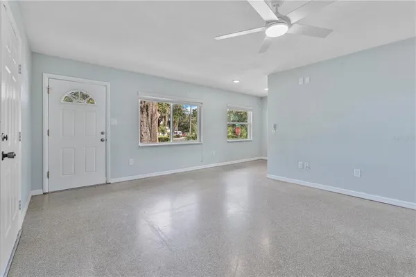 an empty room with windows and fan