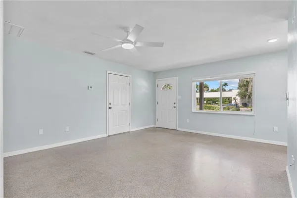 an empty room with windows and fan