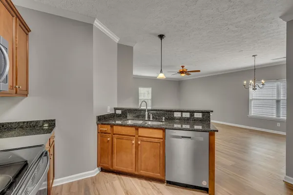 a kitchen with stainless steel appliances granite countertop a stove a sink and a wooden floor