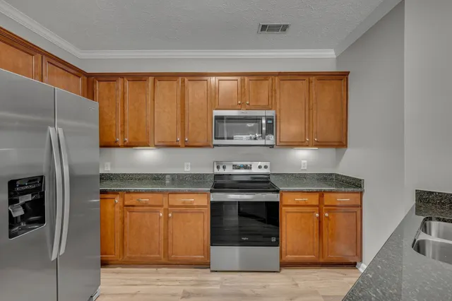 a kitchen with stainless steel appliances granite countertop a refrigerator and a stove top oven
